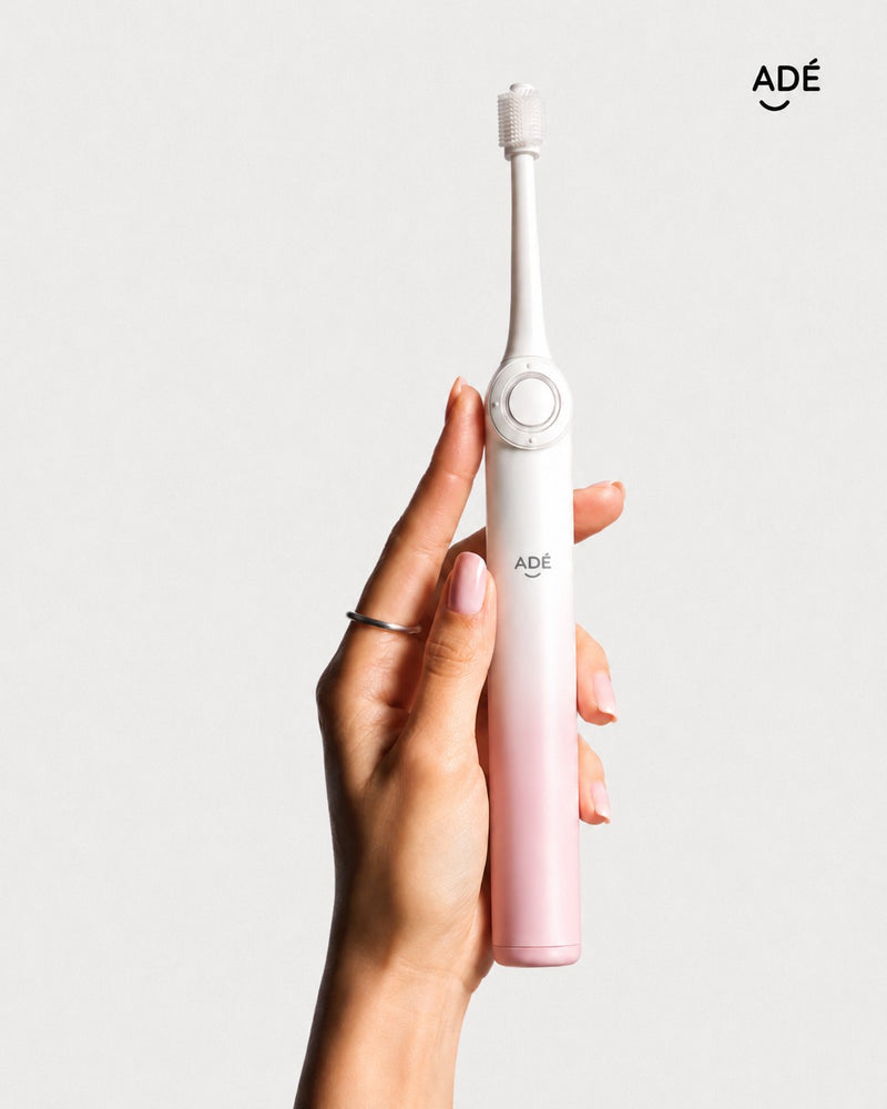 Adé 360 electric toothbrush held in hand