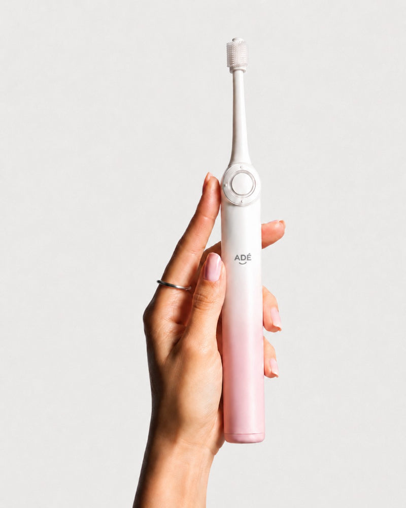 Adé 360 electric toothbrush held in hand
